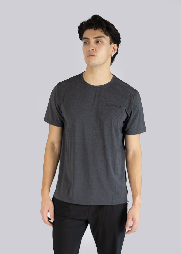 Man wearing a dark gray t-shirt and black pants on a light gray background