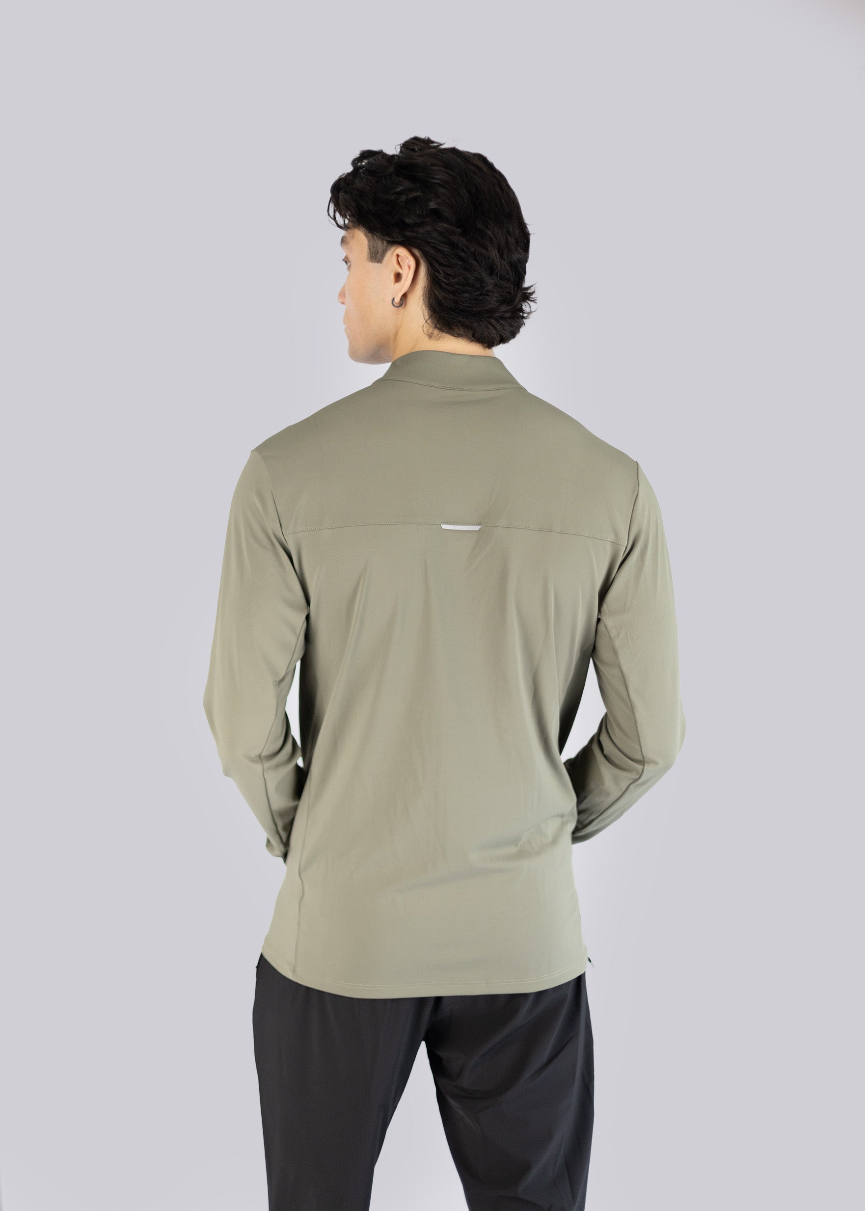 A man wearing an olive long-sleeve Jacket on a gray background