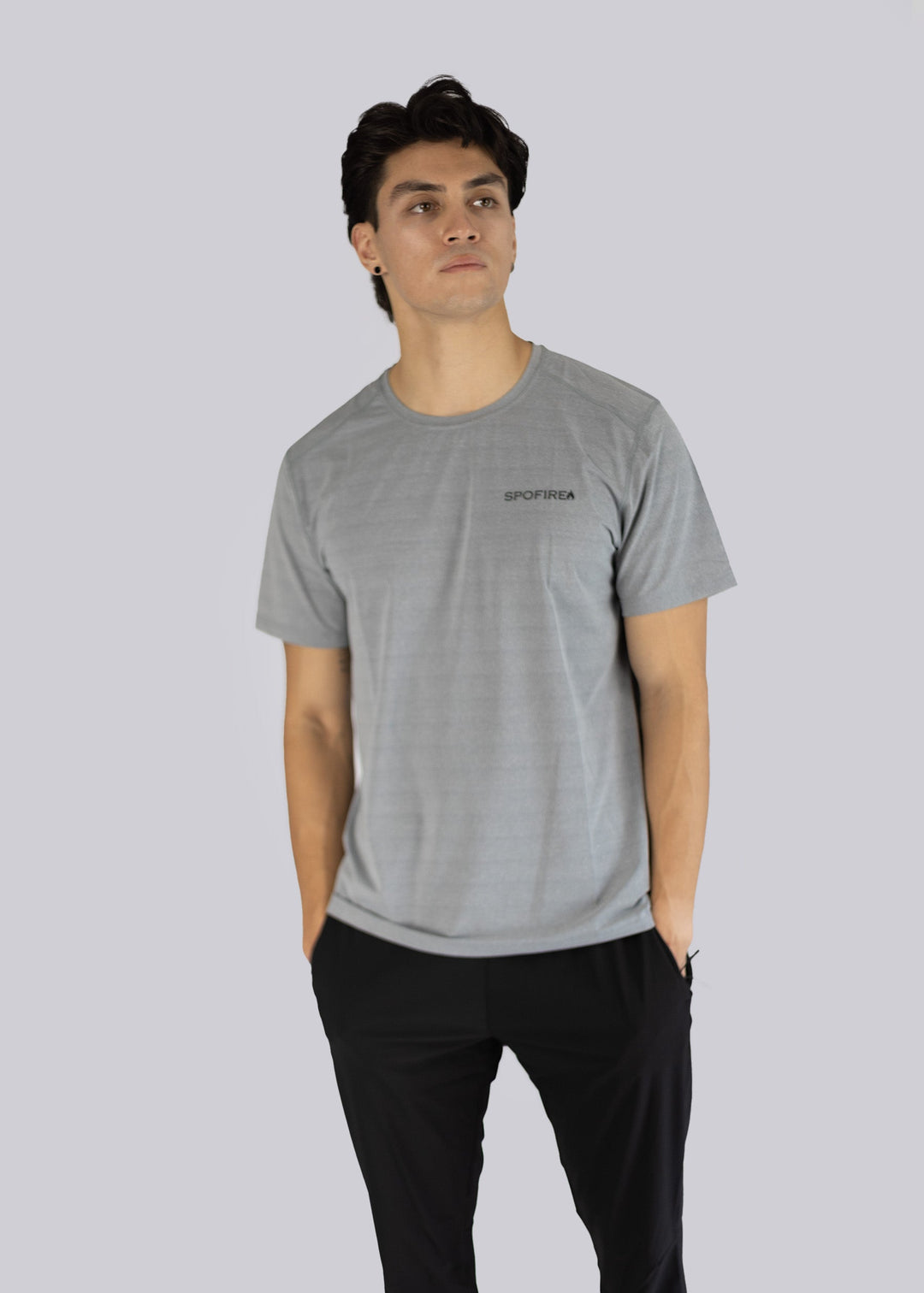 A man wearing a gray t-shirt with the Spofire logo on a light gray background, hands inside his pants pockets