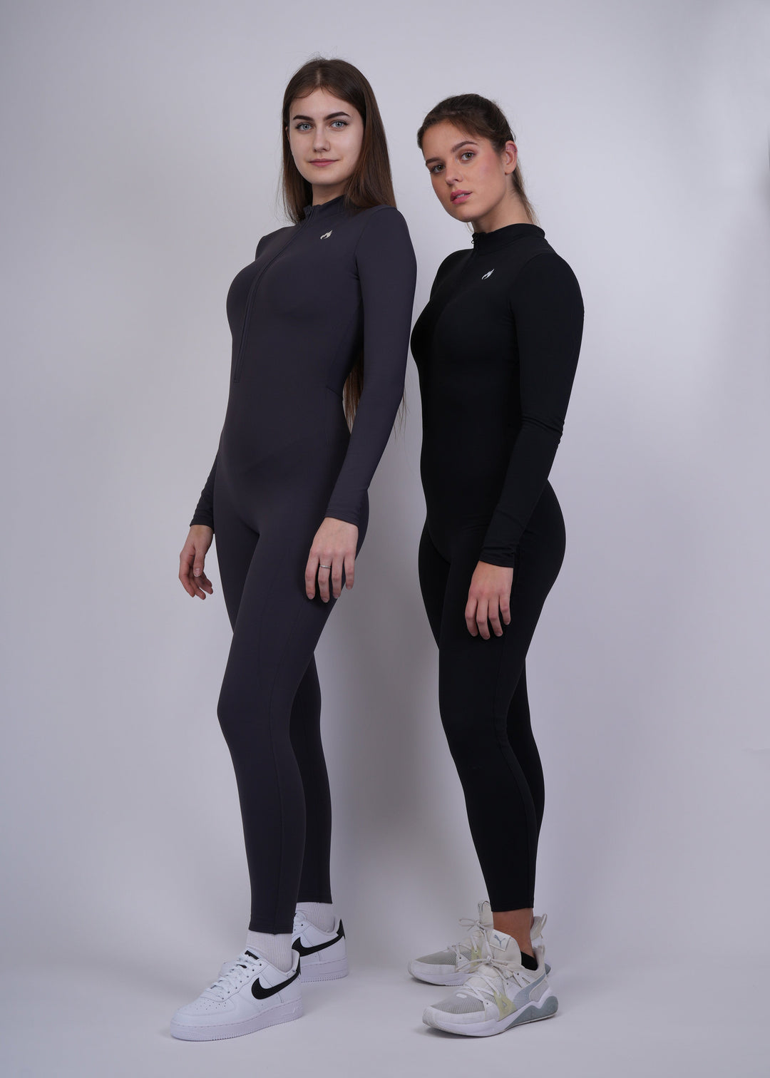 Two Models wearing black and graphite  full-body suits on a white background 