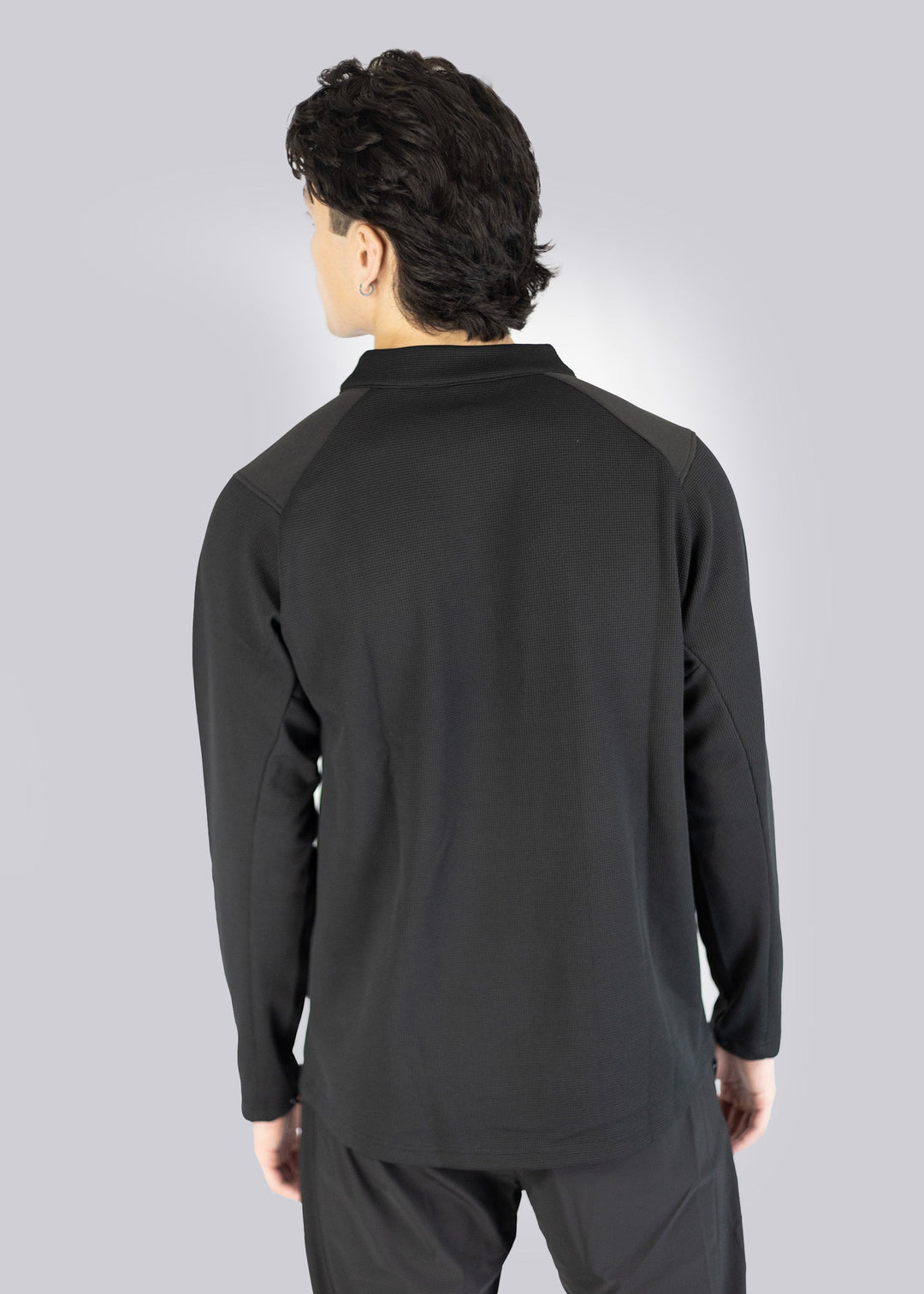 A man wearing a black long-sleeve athletic shirt on a gray background